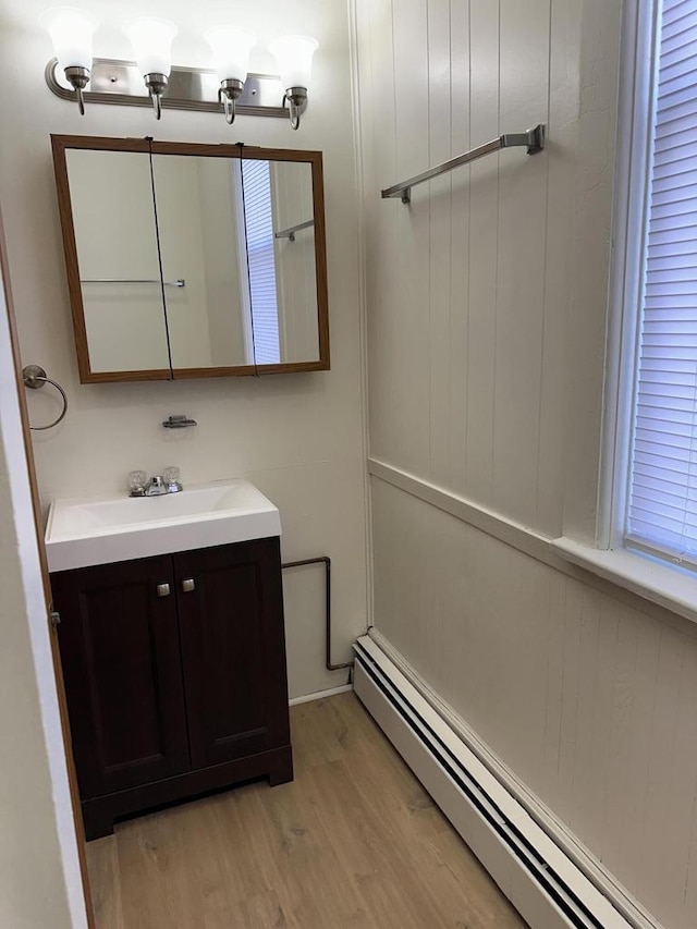 bathroom with a baseboard heating unit, wood finished floors, and vanity