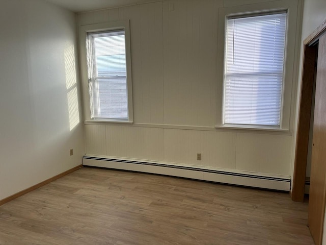 unfurnished room with baseboards, light wood finished floors, and baseboard heating