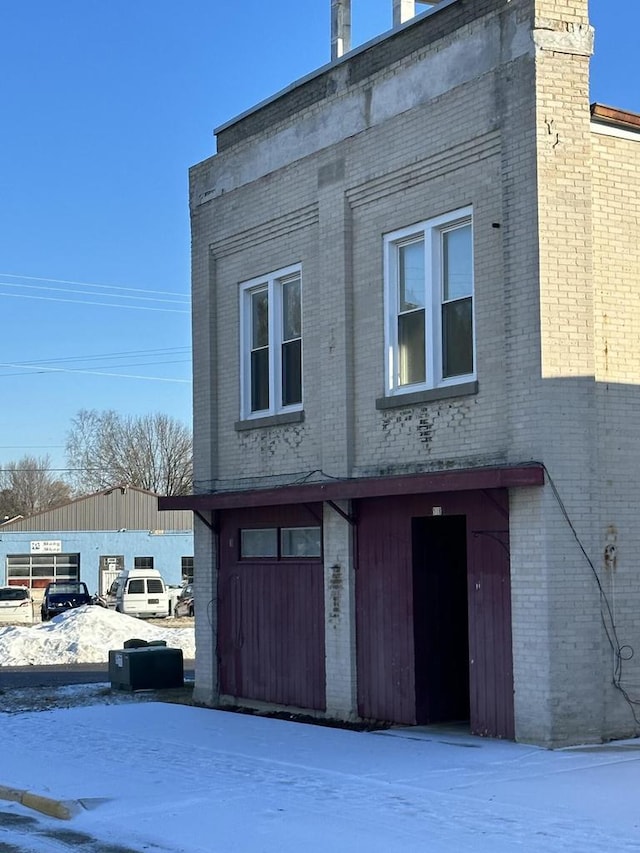 view of snow covered exterior with brick siding