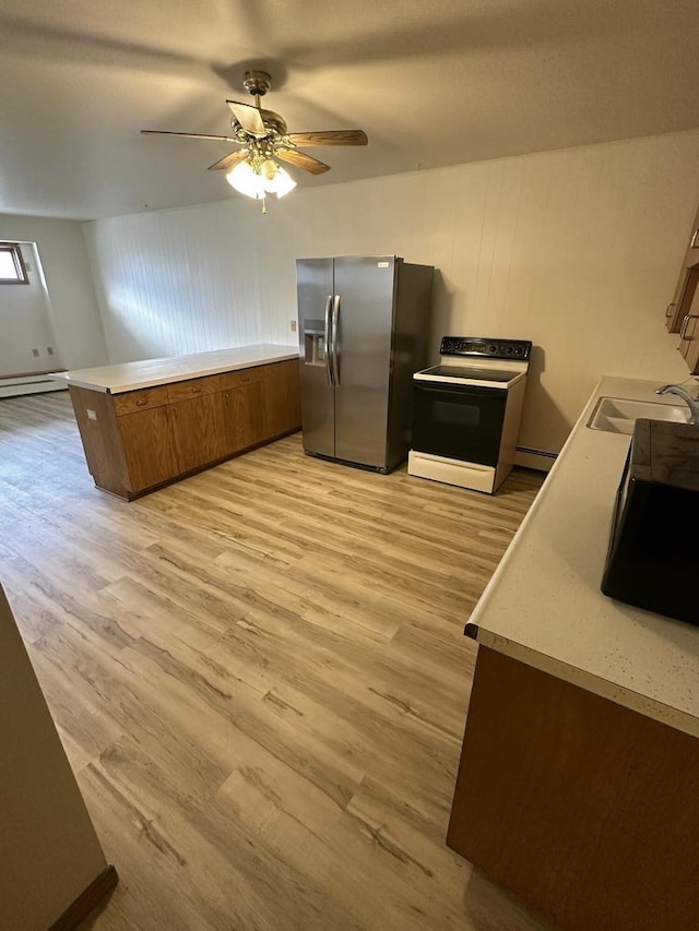 kitchen featuring light countertops, electric range oven, brown cabinetry, a sink, and stainless steel fridge