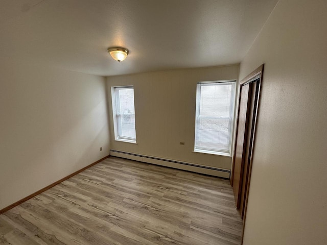 unfurnished room featuring light wood finished floors, baseboard heating, and baseboards