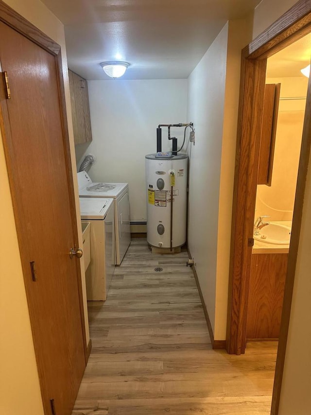 laundry room with light wood-style flooring, a sink, water heater, cabinet space, and washing machine and clothes dryer