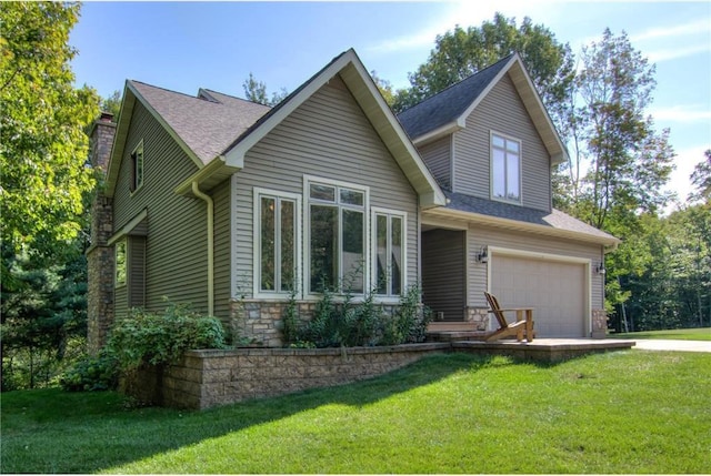 view of front of home with a shingled roof, stone siding, a chimney, an attached garage, and a front lawn