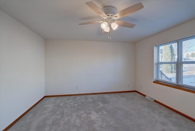 unfurnished room featuring a ceiling fan, visible vents, light carpet, and baseboards