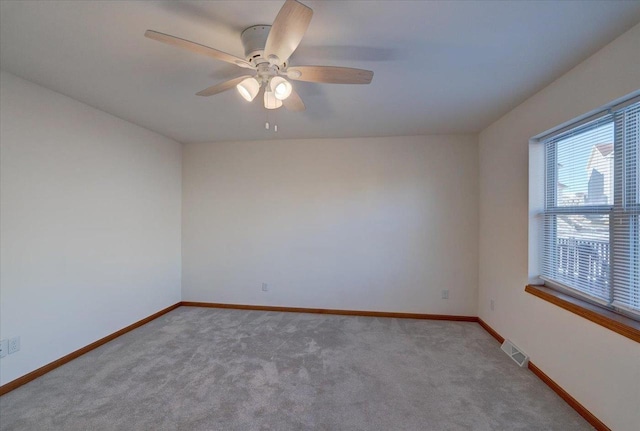 spare room with baseboards, visible vents, ceiling fan, and light colored carpet