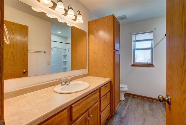 bathroom featuring toilet, wood finished floors, visible vents, vanity, and baseboards