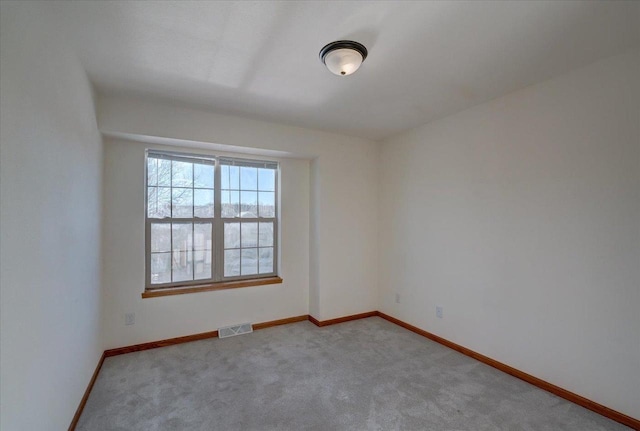 empty room with light colored carpet, visible vents, and baseboards