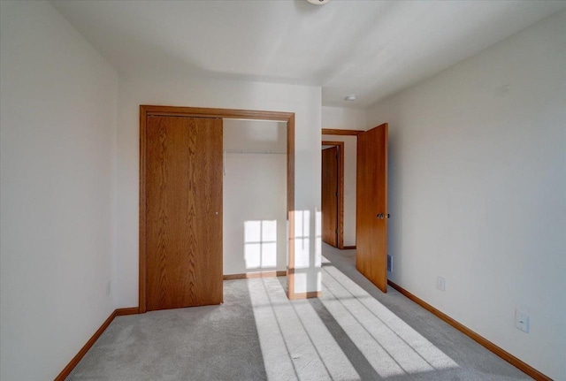 unfurnished bedroom featuring baseboards, a closet, and light colored carpet
