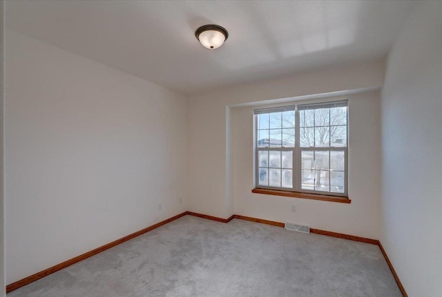 unfurnished room with light carpet, visible vents, and baseboards