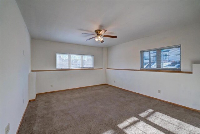 carpeted empty room featuring ceiling fan and baseboards
