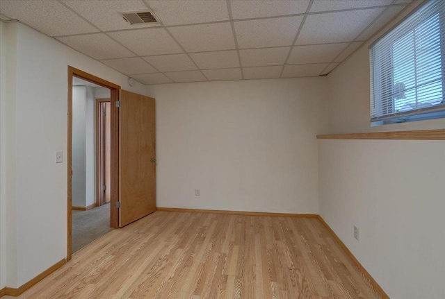 empty room featuring a paneled ceiling, baseboards, visible vents, and light wood finished floors