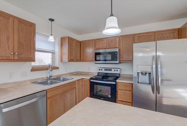 kitchen featuring pendant lighting, stainless steel appliances, a sink, and light countertops