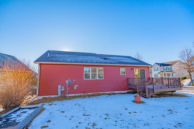 snow covered back of property with a wooden deck