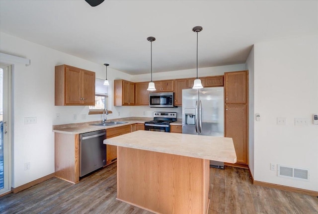 kitchen featuring light countertops, visible vents, appliances with stainless steel finishes, a sink, and a kitchen island