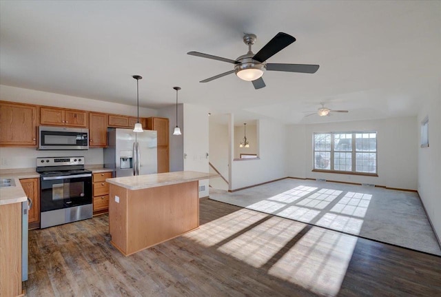 kitchen with a kitchen island, appliances with stainless steel finishes, open floor plan, decorative light fixtures, and light countertops