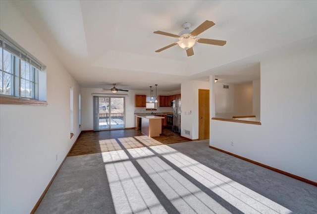 unfurnished living room with dark colored carpet, a raised ceiling, visible vents, and baseboards