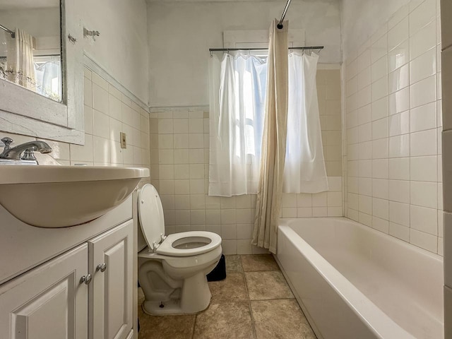 bathroom with tile patterned flooring, toilet, vanity, tile walls, and shower / tub combo with curtain