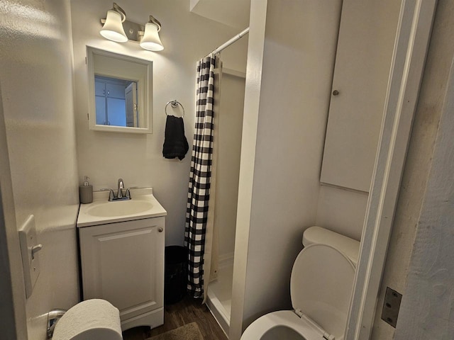 bathroom with toilet, a shower stall, wood finished floors, and vanity