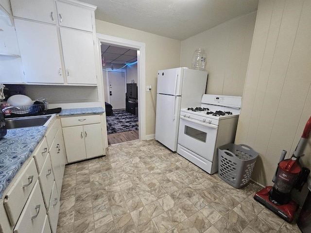 kitchen with light countertops, white appliances, a sink, and white cabinetry