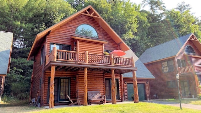 view of front of home featuring driveway, a garage, a shingled roof, a balcony, and a front lawn