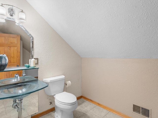 bathroom with tile patterned flooring, toilet, visible vents, baseboards, and vaulted ceiling