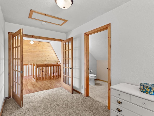 interior space featuring an upstairs landing, light colored carpet, wood walls, and french doors