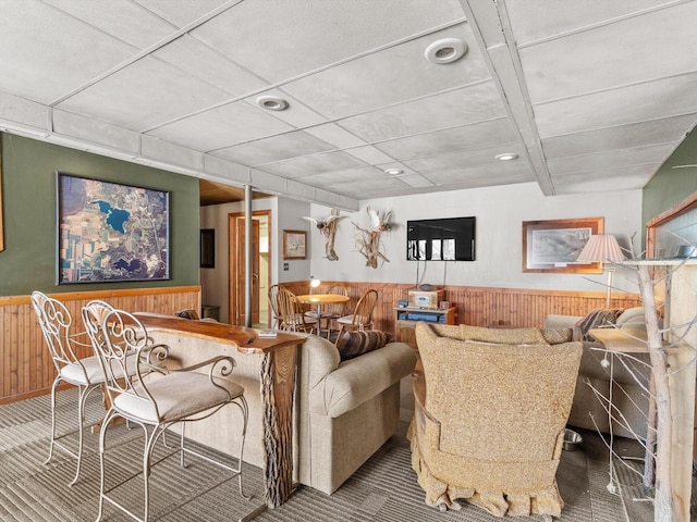 carpeted living room with wood walls, wainscoting, and recessed lighting