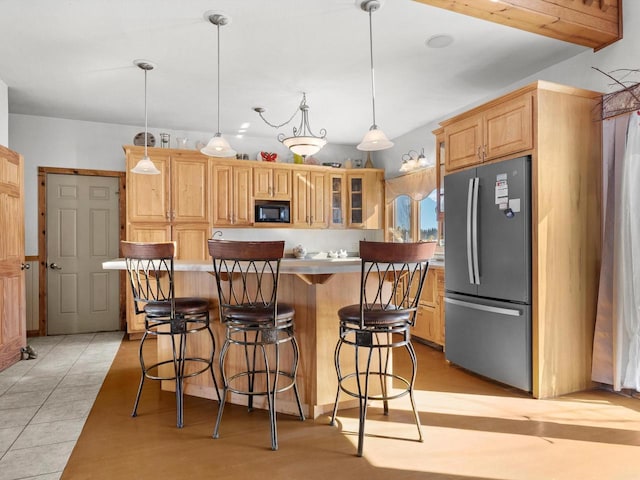 kitchen featuring a kitchen island, glass insert cabinets, decorative light fixtures, freestanding refrigerator, and black microwave