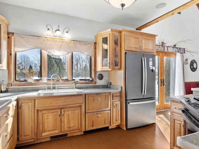 kitchen featuring stainless steel appliances, a sink, visible vents, french doors, and glass insert cabinets