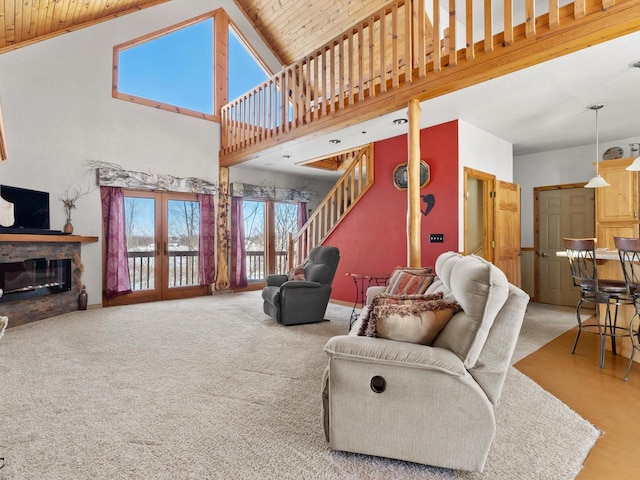 living area with carpet, french doors, a high ceiling, a glass covered fireplace, and stairs