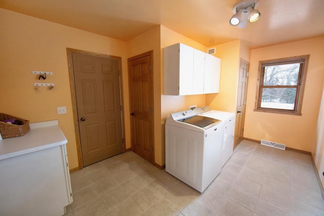 laundry room with washing machine and dryer, cabinet space, visible vents, and baseboards