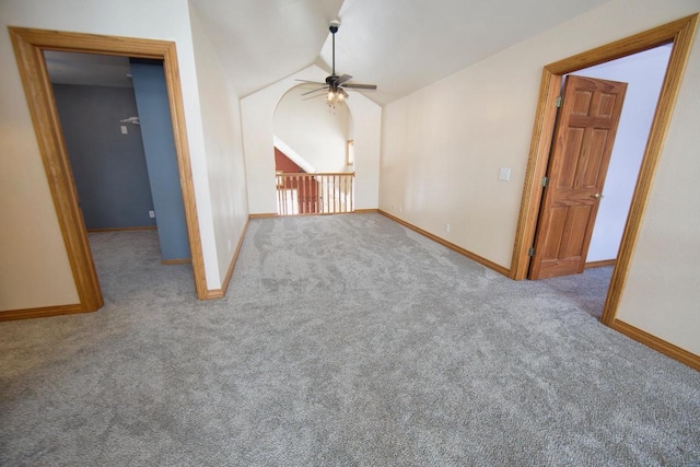 spare room with light carpet, vaulted ceiling, baseboards, and ceiling fan