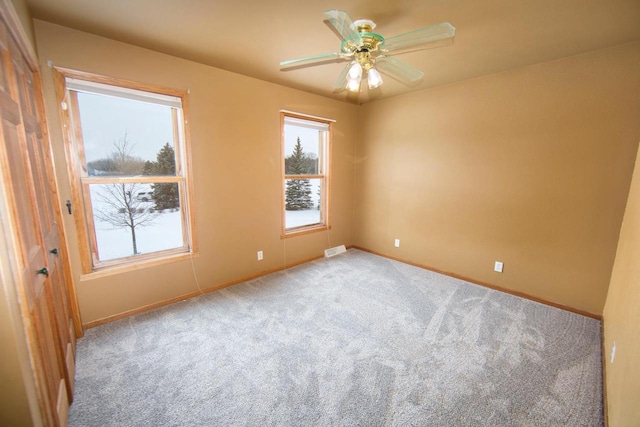 carpeted spare room featuring visible vents, ceiling fan, and baseboards