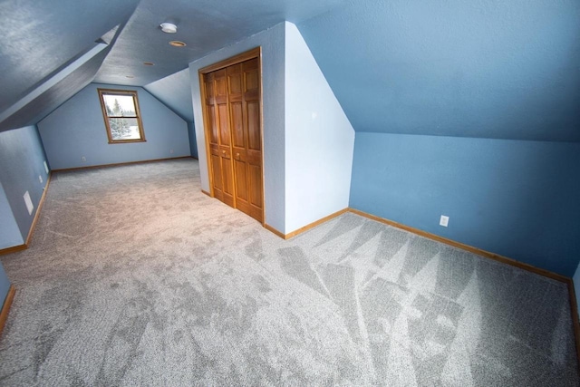 additional living space featuring carpet flooring, vaulted ceiling, and baseboards