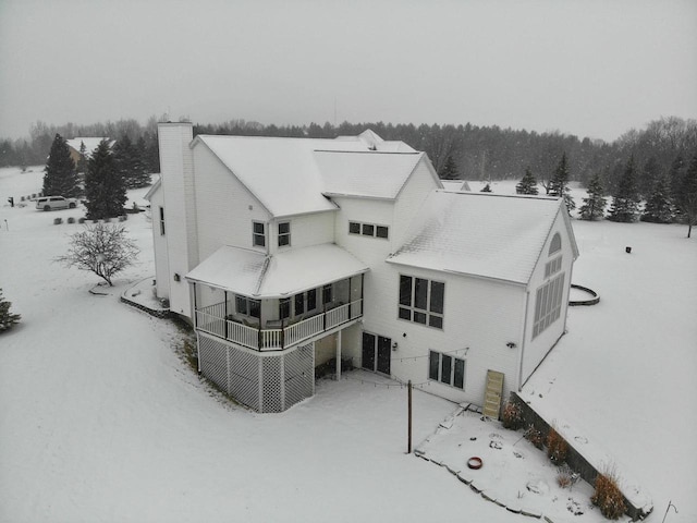 snow covered back of property featuring a chimney