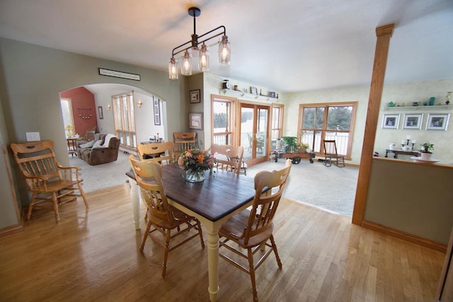 dining room with light wood-style flooring and arched walkways