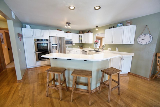 kitchen with stainless steel appliances, glass insert cabinets, white cabinets, and light countertops