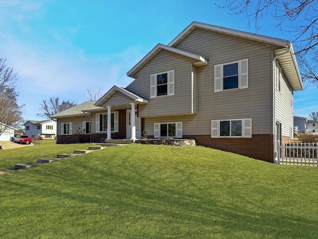 split level home with fence, a front lawn, and brick siding