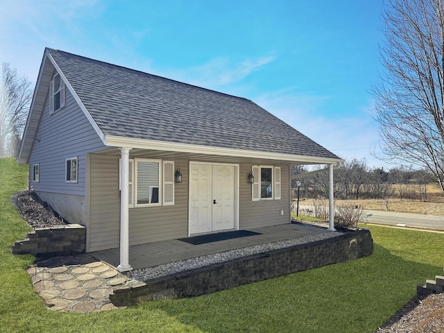 view of front of property featuring covered porch, roof with shingles, and a front yard