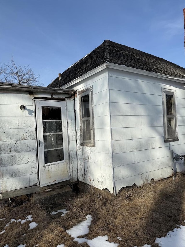 view of side of property with roof with shingles