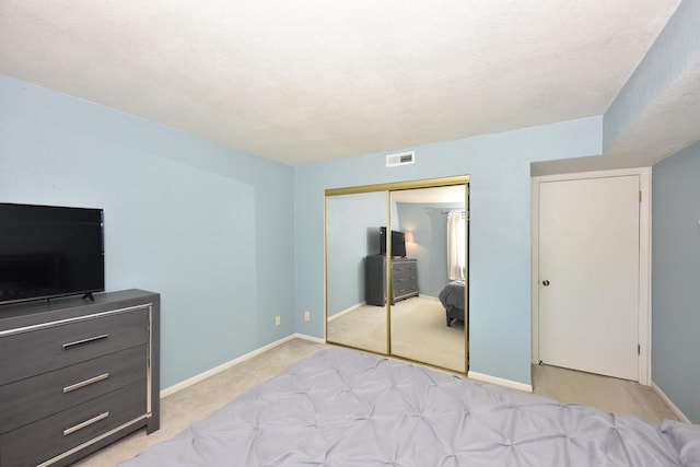 bedroom featuring baseboards, visible vents, light colored carpet, a textured ceiling, and a closet