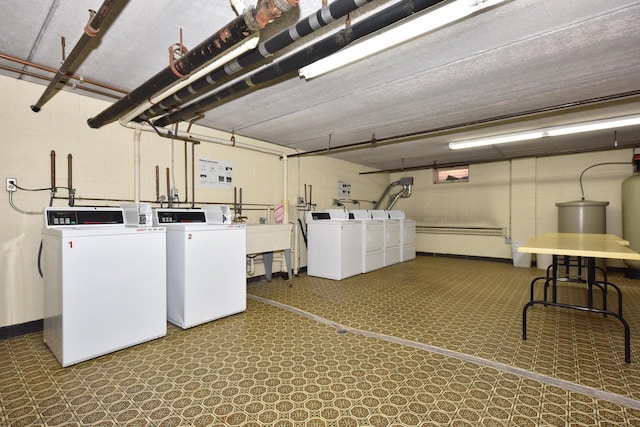 common laundry area featuring concrete block wall, tile patterned floors, a sink, and independent washer and dryer