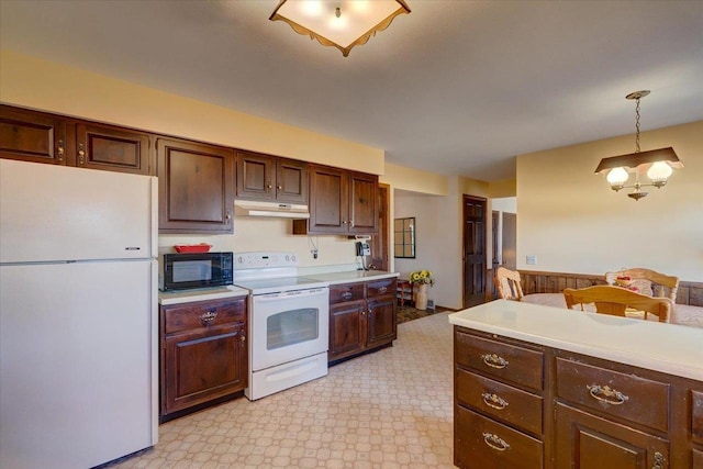 kitchen featuring under cabinet range hood, white appliances, hanging light fixtures, and light countertops