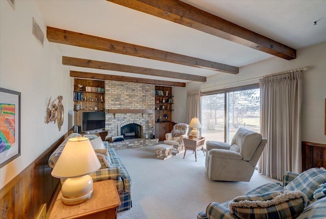 living room featuring visible vents, beam ceiling, carpet, and a brick fireplace