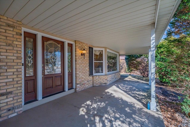 view of exterior entry with covered porch and brick siding