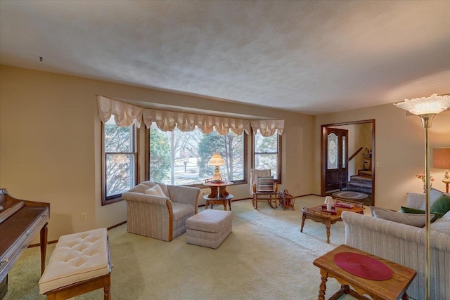 carpeted living area featuring stairway and baseboards