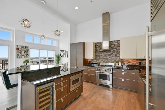 kitchen featuring built in appliances, beverage cooler, backsplash, wall chimney exhaust hood, and modern cabinets