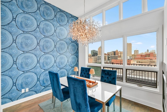 dining space with a view of city, wood finished floors, plenty of natural light, and a chandelier