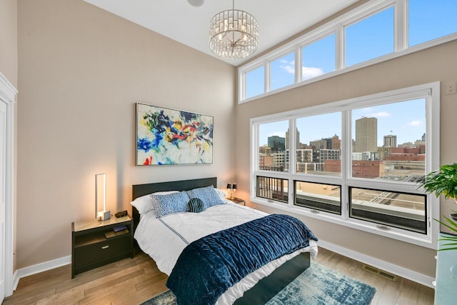 bedroom with a view of city, visible vents, baseboards, and wood finished floors