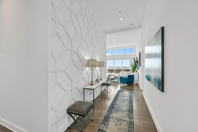 corridor featuring dark wood-style floors, an accent wall, recessed lighting, and baseboards